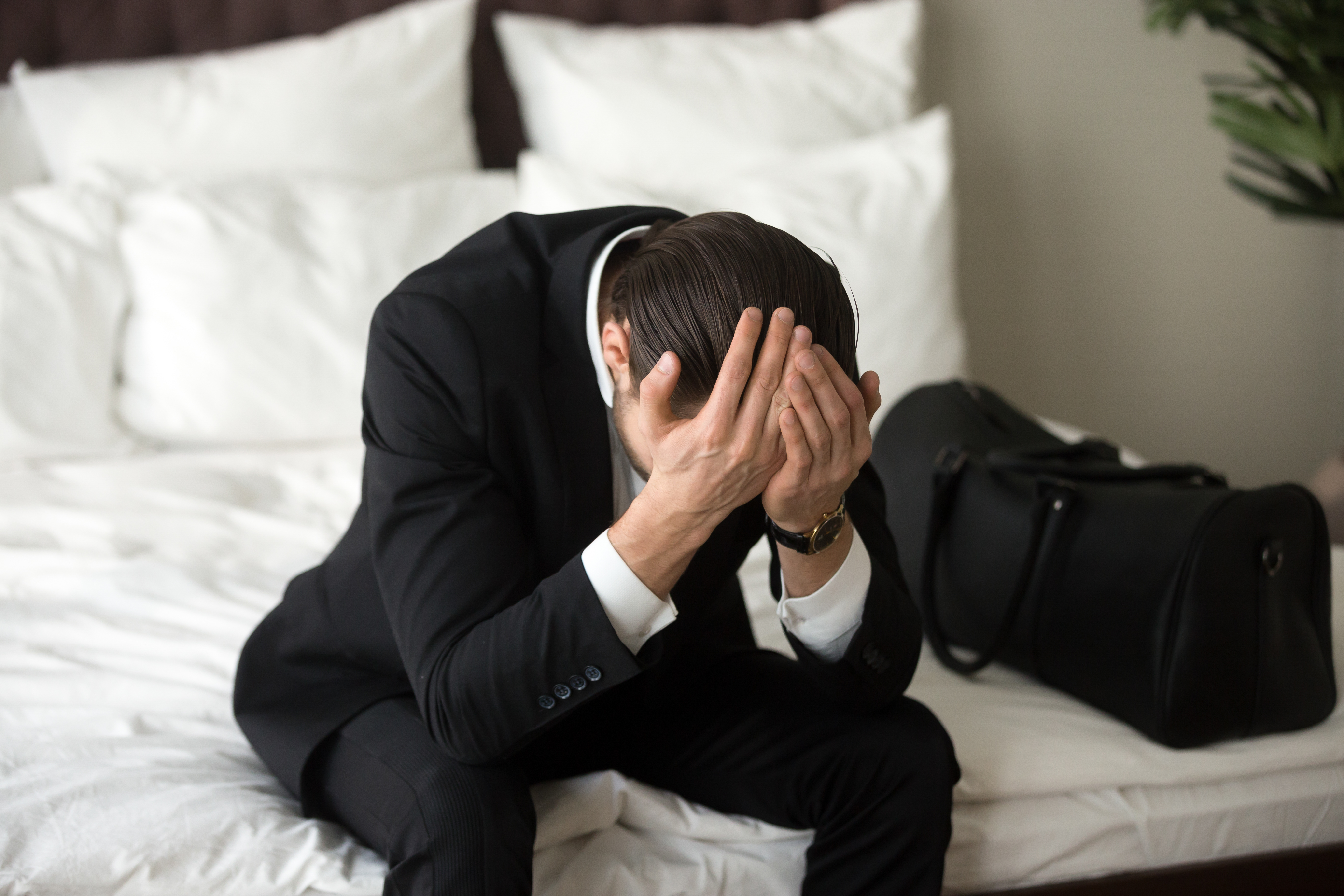 stressed-upset-businessman-sitting-bed-having-headache