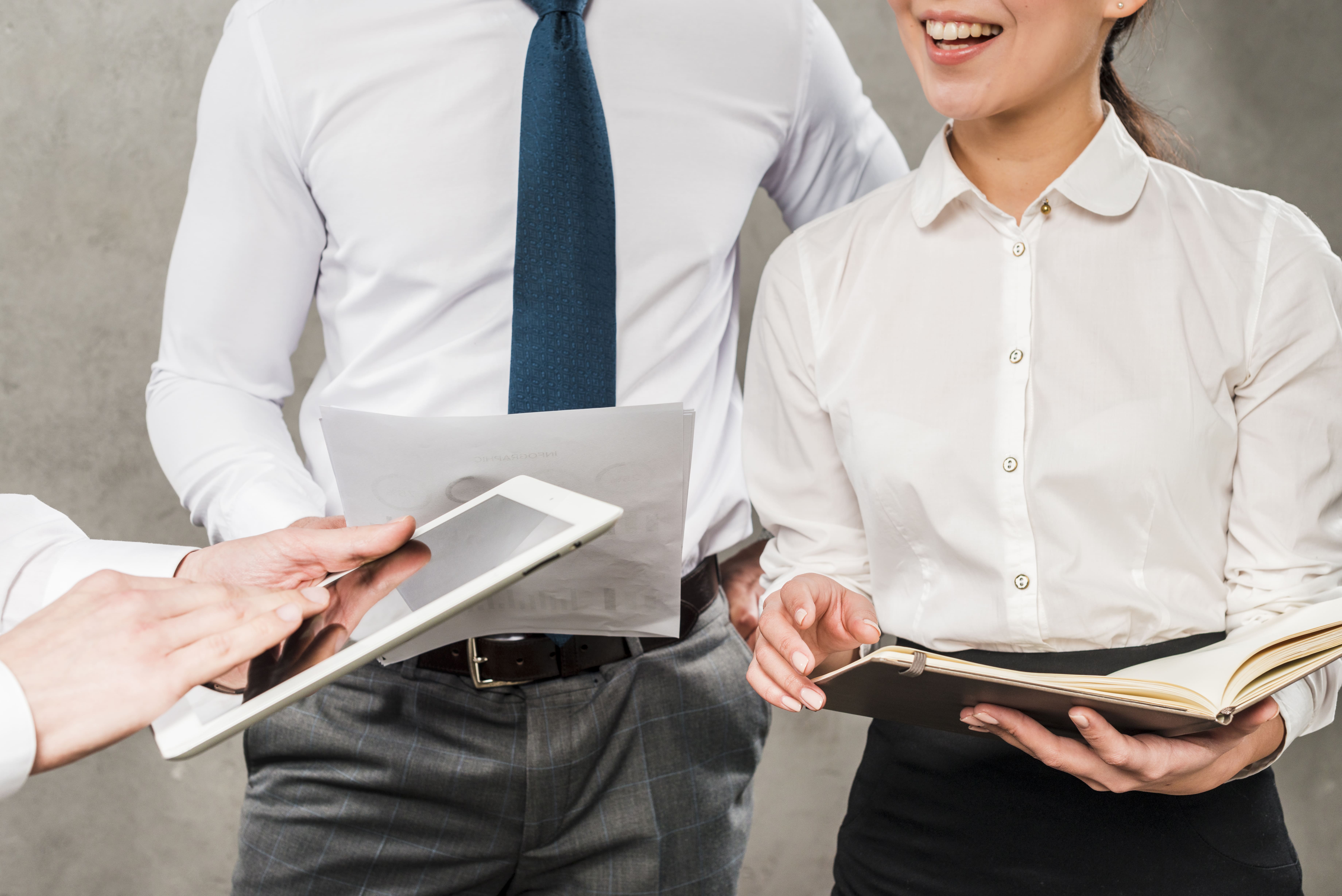 close-up-businesspeople-working-together-against-grey-wall