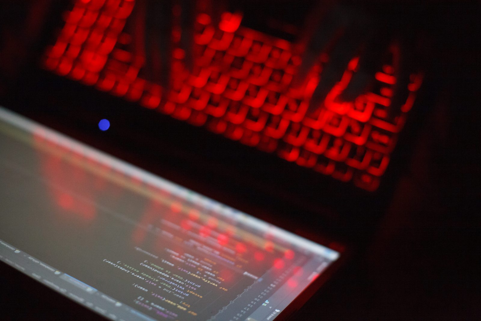 person-typing-laptop-keyboard-with-red-backlight-blurred