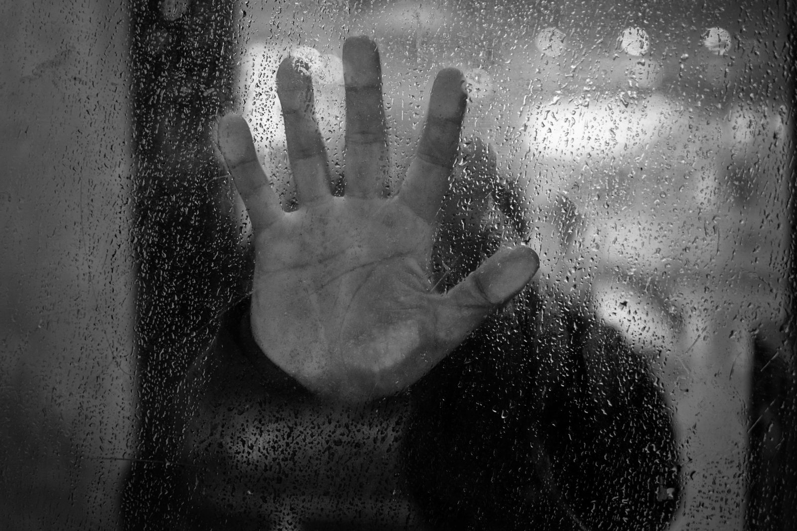 close-up-hand-touching-wet-glass-window