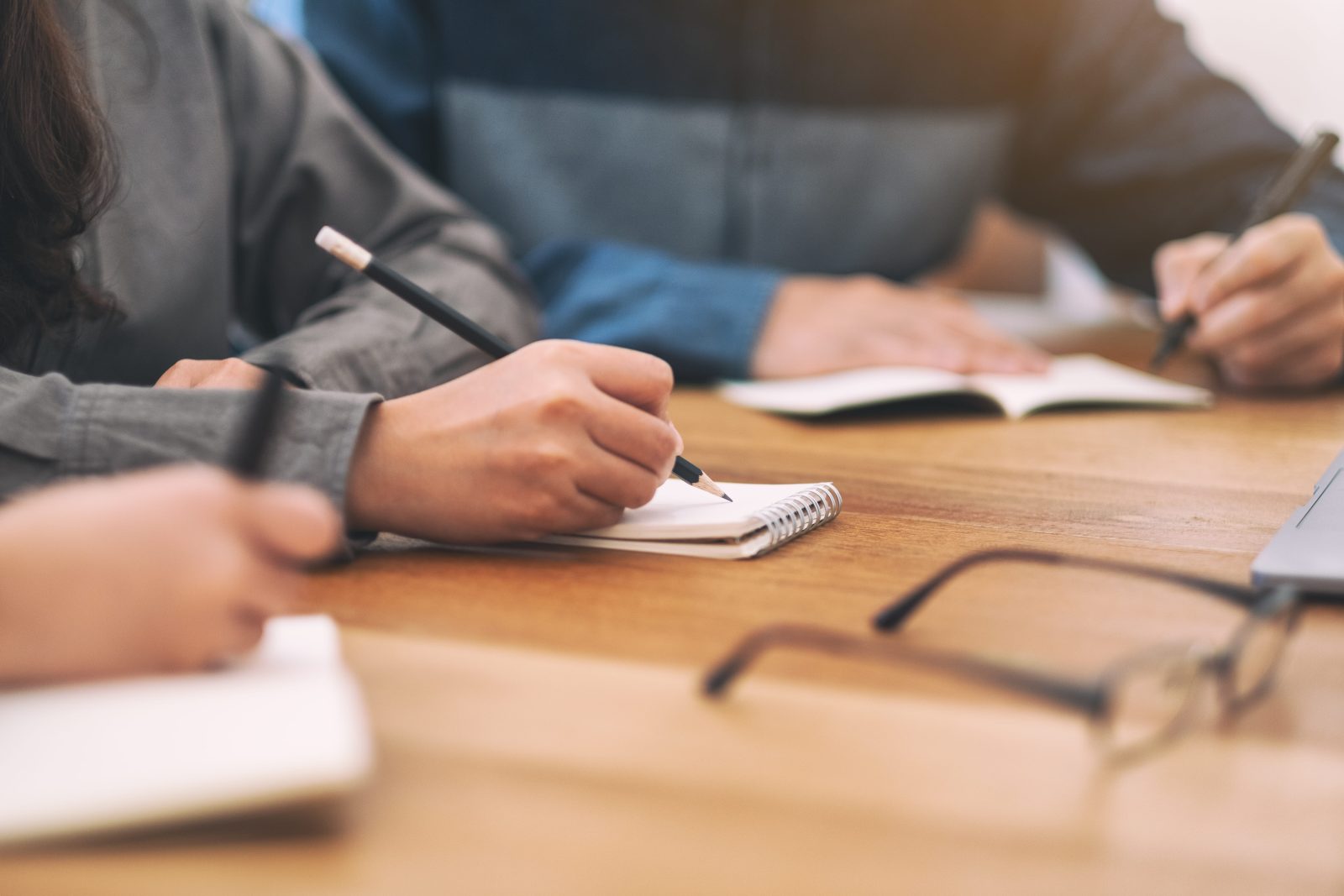 closeup-image-people-writing-blank-notebook-together-wooden-table