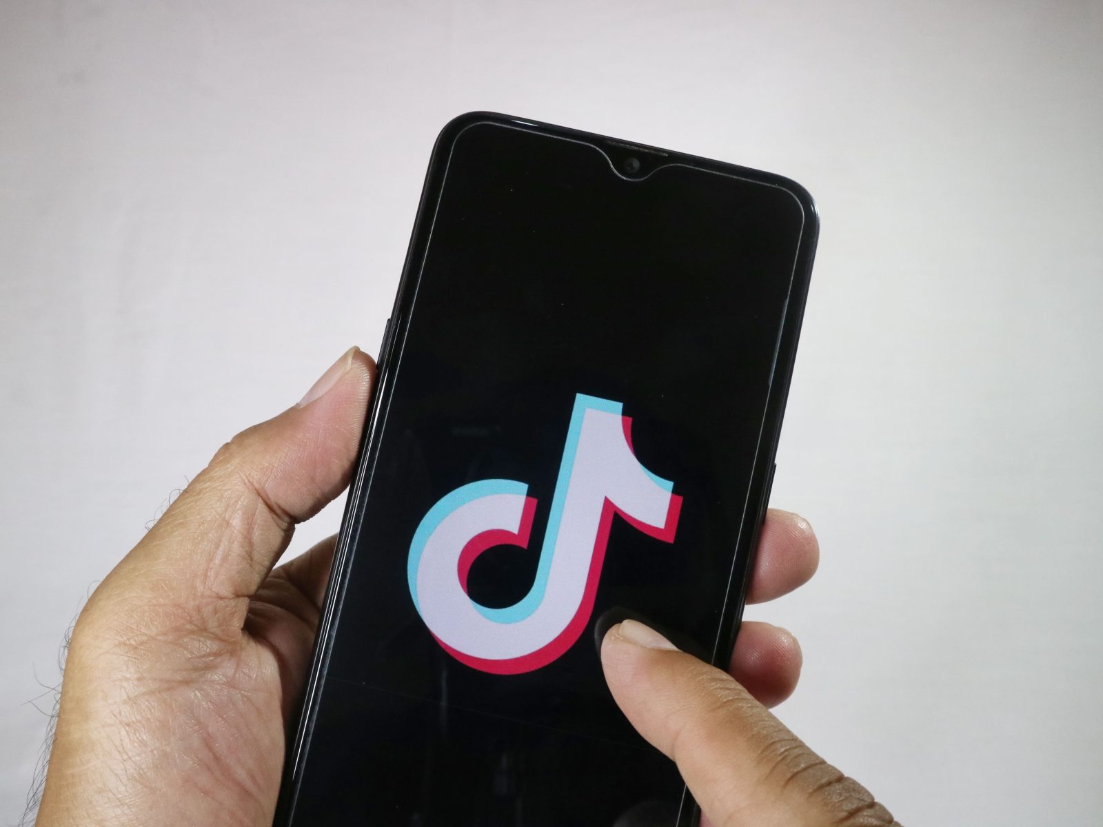 hand-holding-mobile-phone-with-finger-touch-tiktok-logo-screen